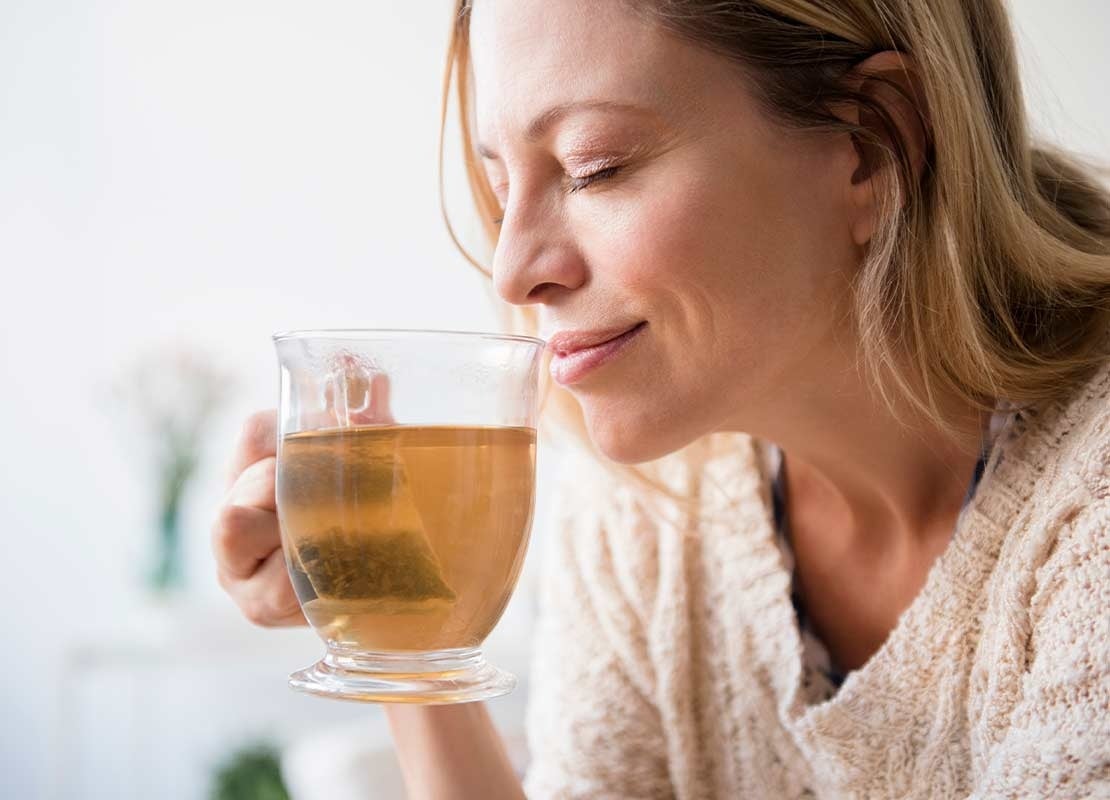 Mujer bebe plácidamente uno de los tipos de té e infusiones