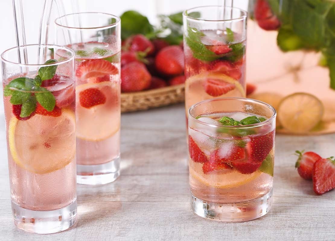 4 vasos de diferentes tamaños y formas con mocktails de fresa, rodajas de limón y hojas de hierbabuena