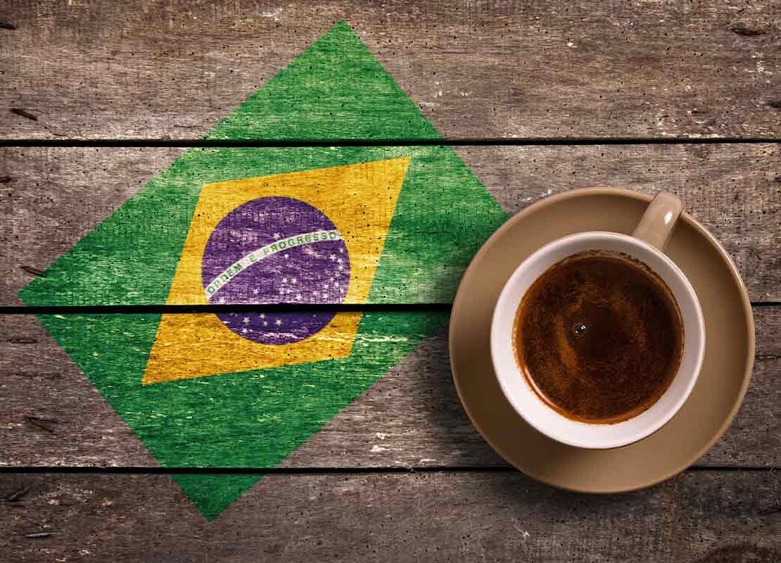 Sobre una tabla está el dibujo de la bandera de Brasil y al lado una taza de café