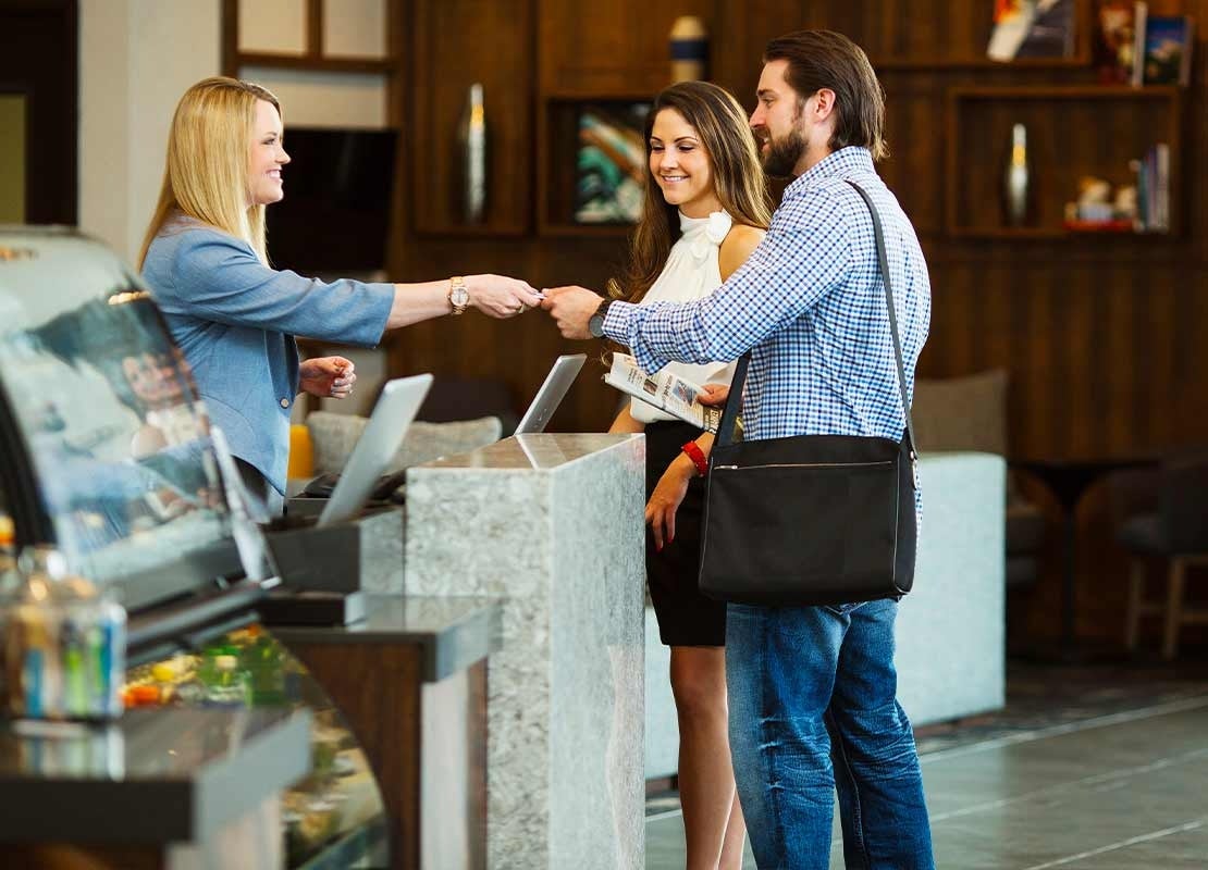 Recepcionista registra en un portátil el pago de dos huéspedes en un hotel