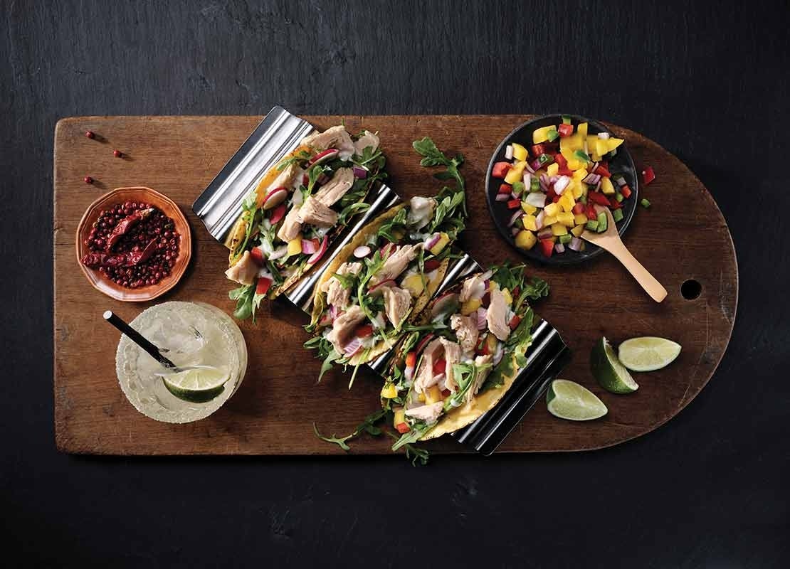 3 tacos de vegetales con pollo servidos a la mesa con limonada y taza de verduras