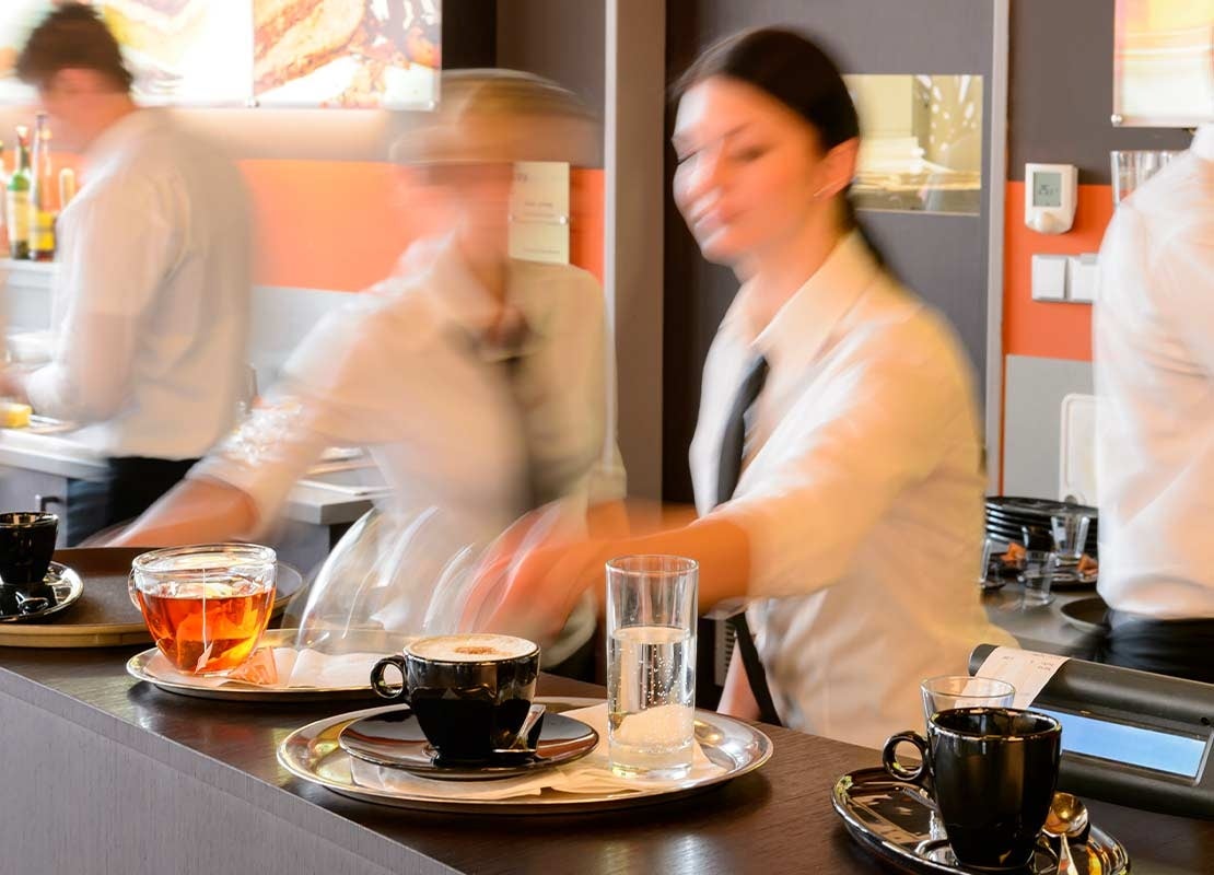 Equipo de una cafetería sirve y prepara comidas y bebidas tras la barra de un negocio