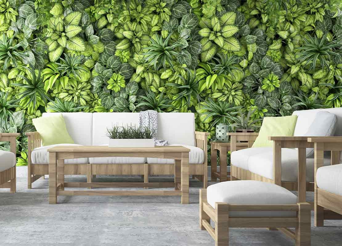 Terraza de restaurante con sofá, sillones, mesa de centro y una pared con plantas en macetas