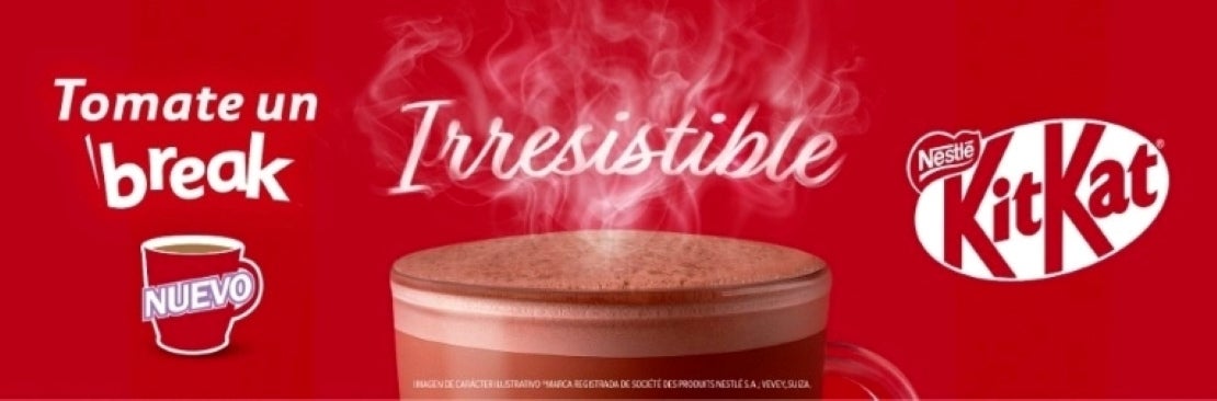 Una taza de chocolate caliente NESTLÉ® KITKAT® con vapor sobre un fondo rojo con el logo de la marca