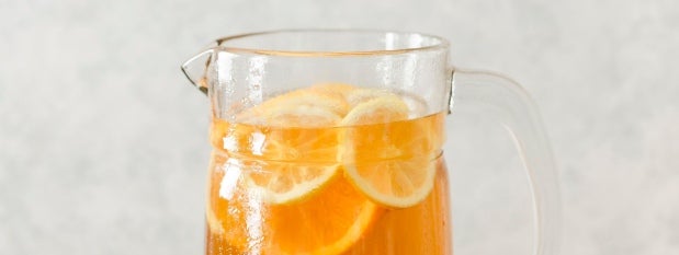 Una jarra de vidrio con bebida NESTEA® acompañada de limón.