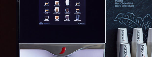 Máquina de café en primer plano, sirve café en vaso NESCAFÉ®.