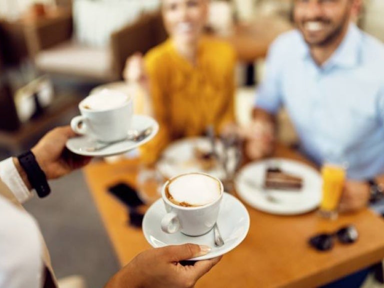 Camarera sirviendo café a una pareja en el restaurante de un hotel