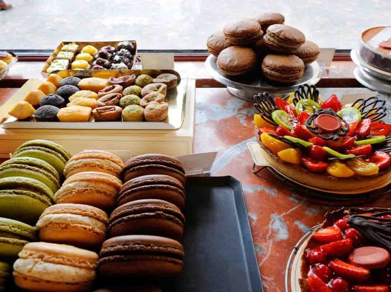 Mesa de postres con diferentes opciones como tartas, galletas, fruta, donas, entre otros