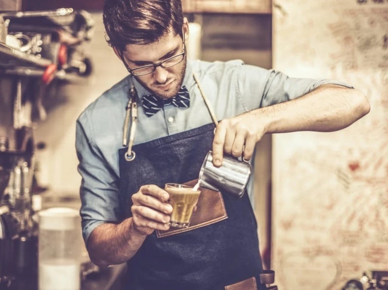 Joven barista preparando un café