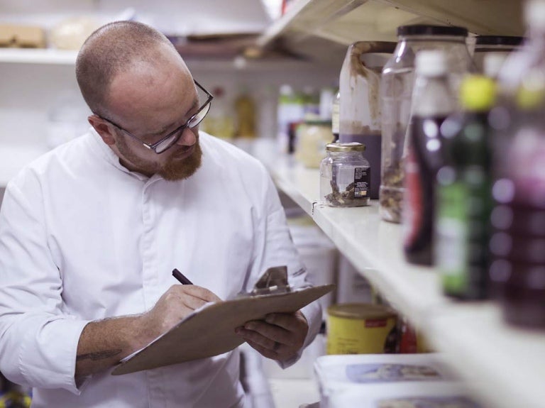 Chef ejecutivo en el almacén de un restaurante revisa y hace inventario de los ingredientes e insumos