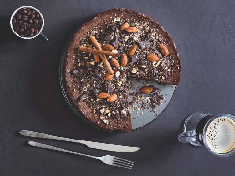 Vista superior de tarta de mousse de chocolate con almendras y café sobre fondo de pizarra que hacen un maridaje perfecto