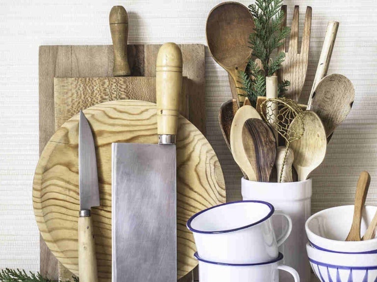 Utensilios de cocina en madera como diversas tablas de picar, cuchillos, cucharas, mezcladores, espátulas, tazas y pocillos