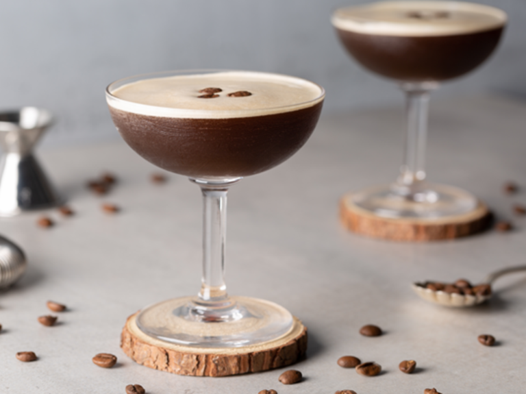 Cócteles sin alcohol como dos Martini Espresso sobre un portavasos de madera, decorados con granos de café