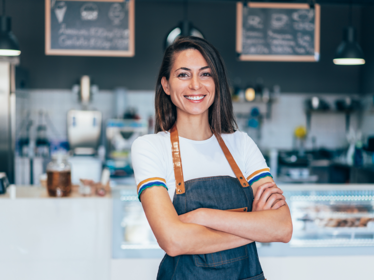 Mujer barista con los brazos cruzados y sonrisa