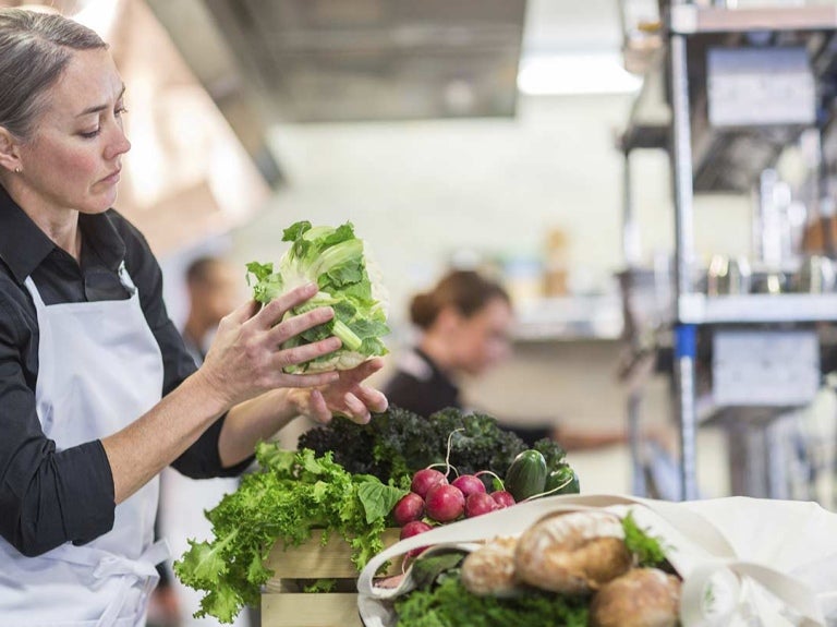 Chef revisa una lechuga y otras frutas y verduras antes de desinfectar en la cocina de un restaurante