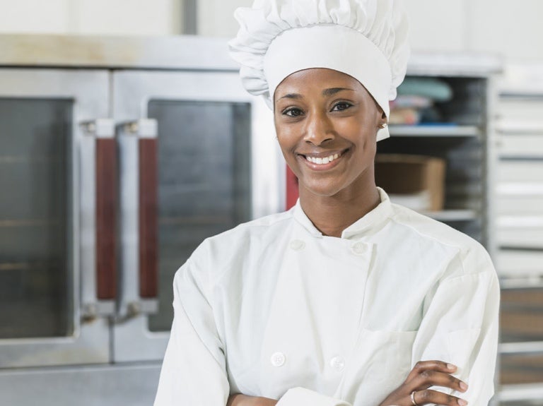 Mujer en una cocina comercial sonriendo en su emprendimiento de negocio de comida