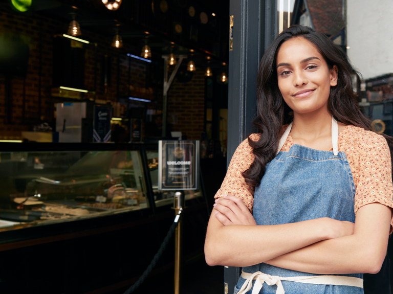 Dueña de un negocio de food service sonriendo frente a su local lista para ofrecer menús nocturnos