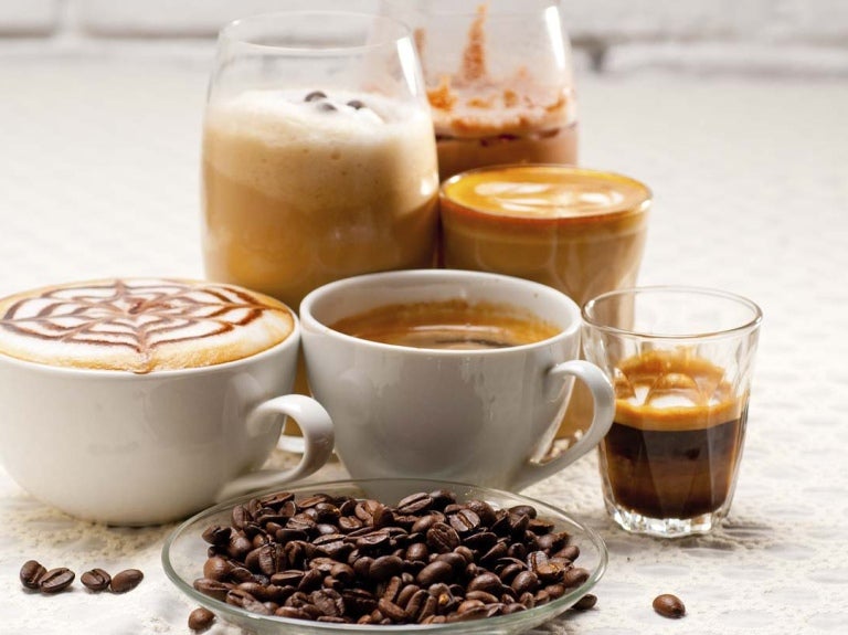 Granos de café tostados y 6 bebidas en diversos tipos de tazas como espresso, café frío, americano, entre otros