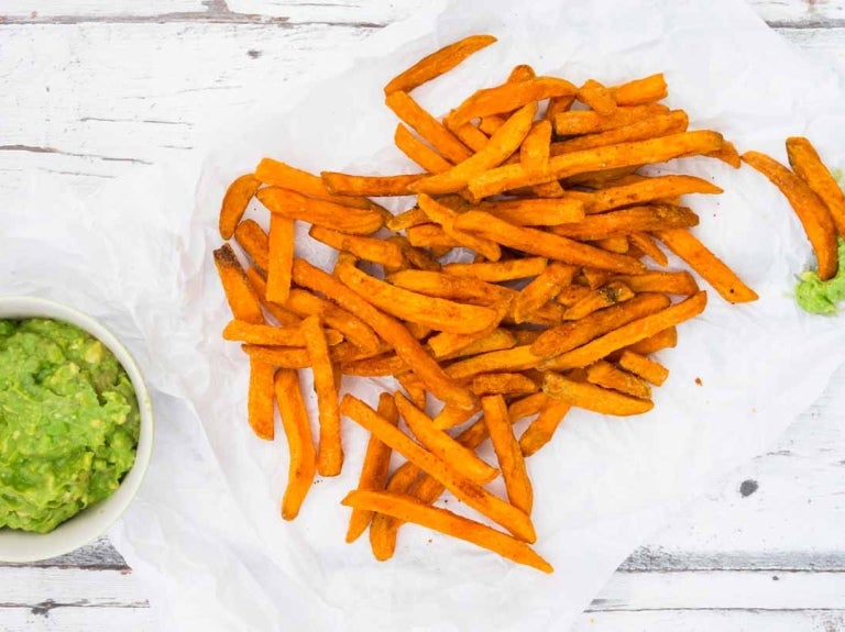 Plato de porcelana con papas fritas en bastones acompañadas de una taza de guacamole