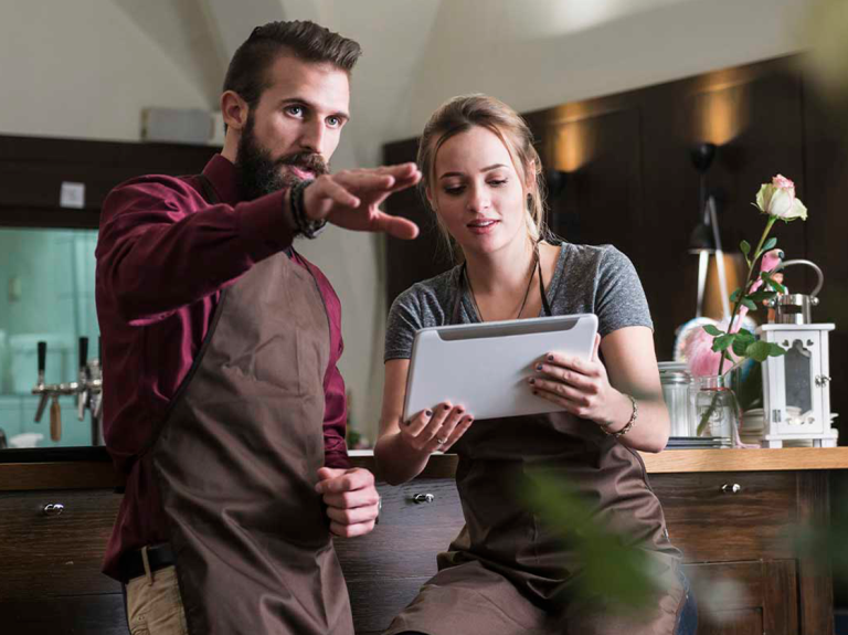 Dos empleados tomando decisiones a partir de una IA para restaurantes que consultan en una tablet
