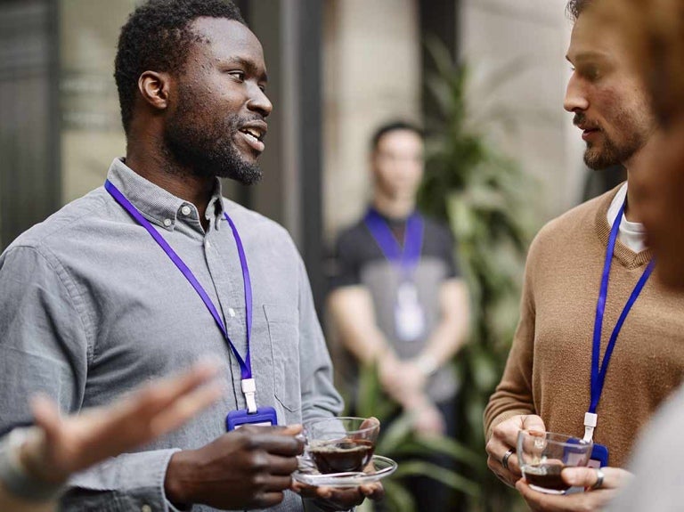 Grupo de trabajadores conversan mientras disfrutan de una taza de café durante un coffee break