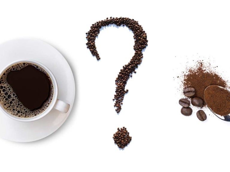 Signo de interrogación hecho de granos de café tostados, cuchara con café soluble y una taza de la bebida