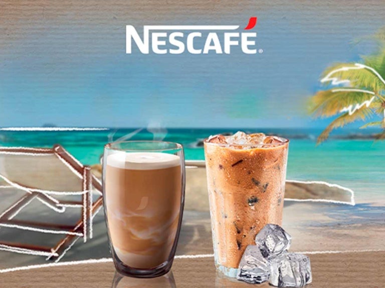 Dos vasos de café frío con leche y hielo elaborados con NESCAFÉ®. Al fondo una playa