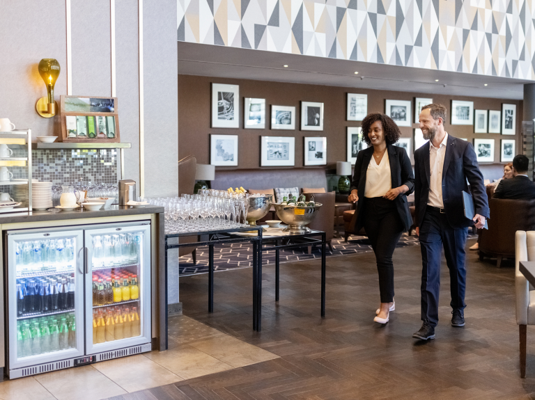 Hombre junto a mujer caminado en el desayunador de un hotel