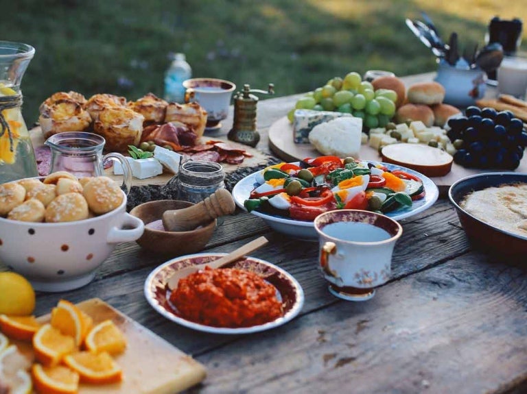 Mesa con diferentes tipos de comidas y bebidas, servida al aire libre