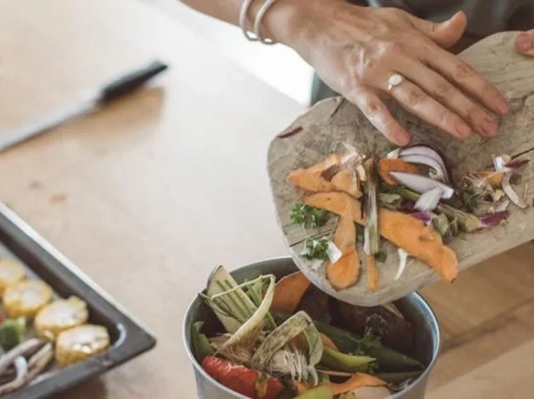 Manos de mujer almacenando desperdicios de alimentos en un recipiente