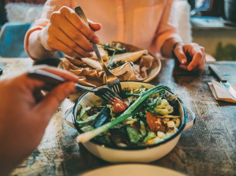 Dos personas disfrutan de ensaladas compuestas y frescas, y bebidas en un restaurante acogedor
