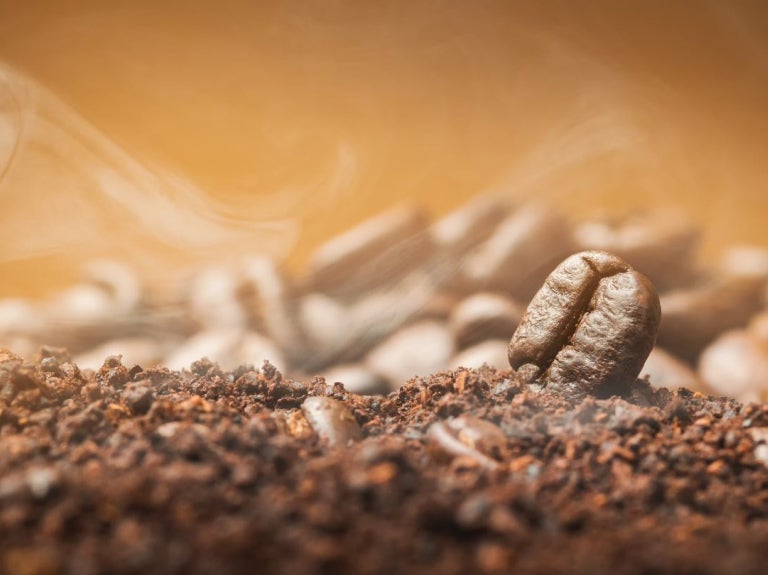 Granos de café y soluble suspendidos en el aire en movimiento sobre fondo oscuro