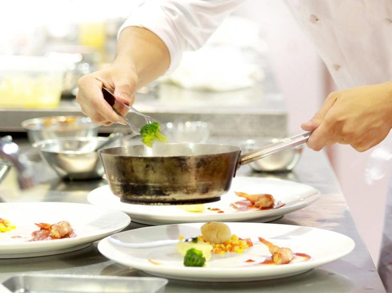 Chef sirviendo un plato gourmet en una cocina profesional, utilizando food solutions
