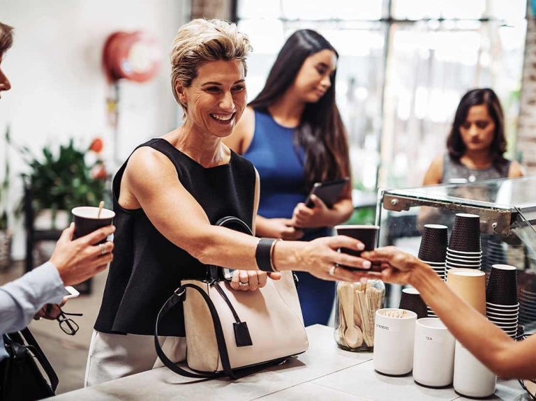 Personas reciben vasos desechables de café en un mostrador de una tienda de conveniencia