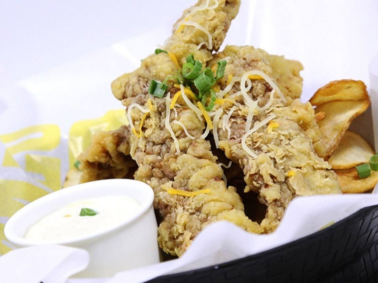 Un canasto con tiras de pollo empanizadas y salsa dip, ideal para un menú fácil y rápido.