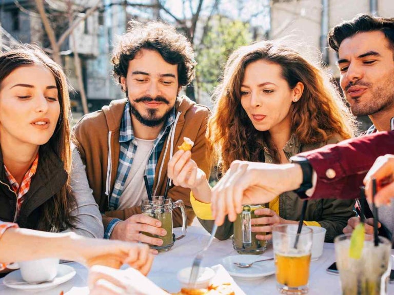 Grupo de millennials comparte comida y bebidas al aire libre, representando distintos tipos de consumidores.