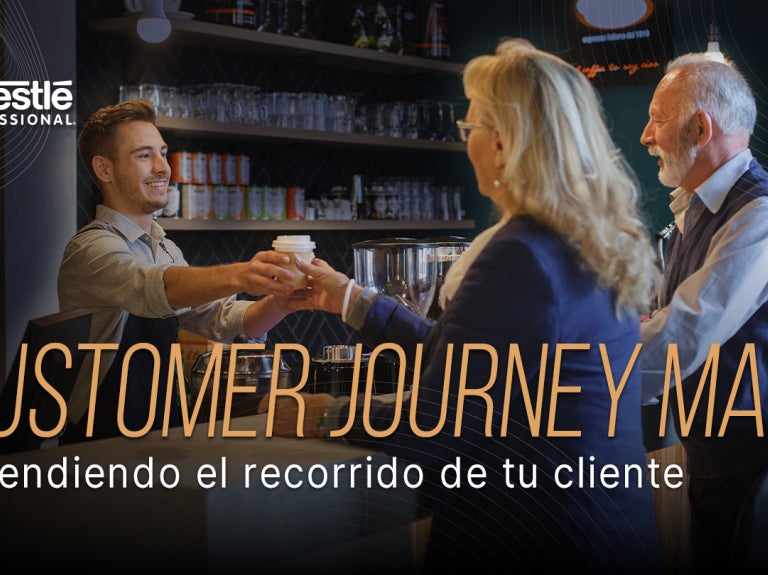 Barista entrega una bebida mientras interactúa con clientes en el mostrador de una cafetería