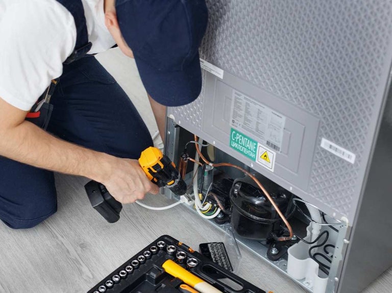 Técnico realiza mantenimiento de equipos de cocina en un sistema de refrigeración profesional.