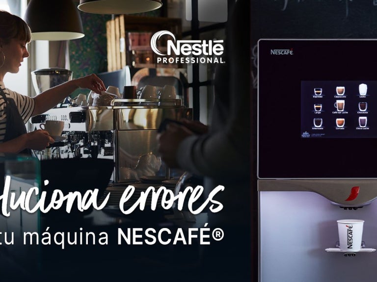 Barista opera una máquina de café, al lado la pantalla de un equipo automático en una cafetería.