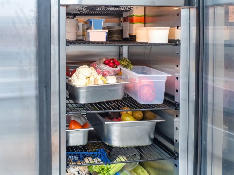 Refrigerador con alimentos organizados para conservar propiedades organolépticas en cocina profesional.
