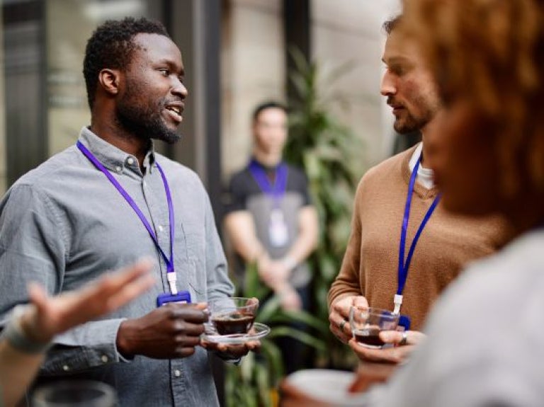 Grupo de personas conversando mientras sostienen tazas de café en un networking