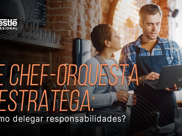 Dos personas revisan una tablet en cocina profesional con el texto sobre delegar responsabilidades