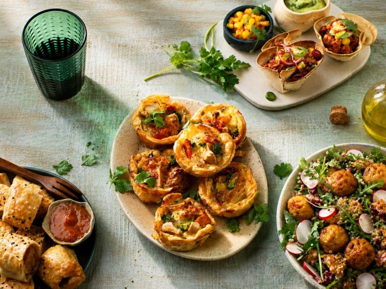 Plato con tartaletas saladas decoradas con hierbas y acompañamientos sobre mesa