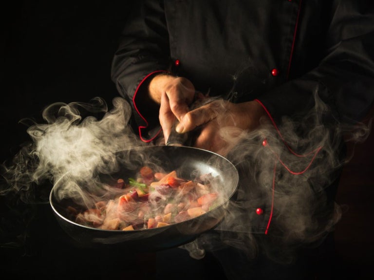 Chef sirviendo un plato gourmet en una cocina profesional, utilizando food solutions