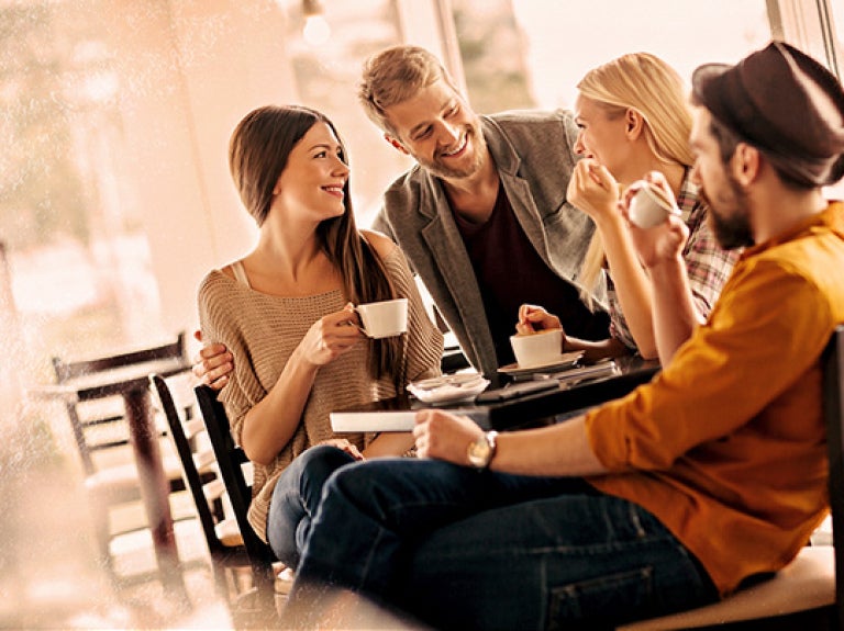 Grupo de personas sentadas conversando mientras toman café en mesa