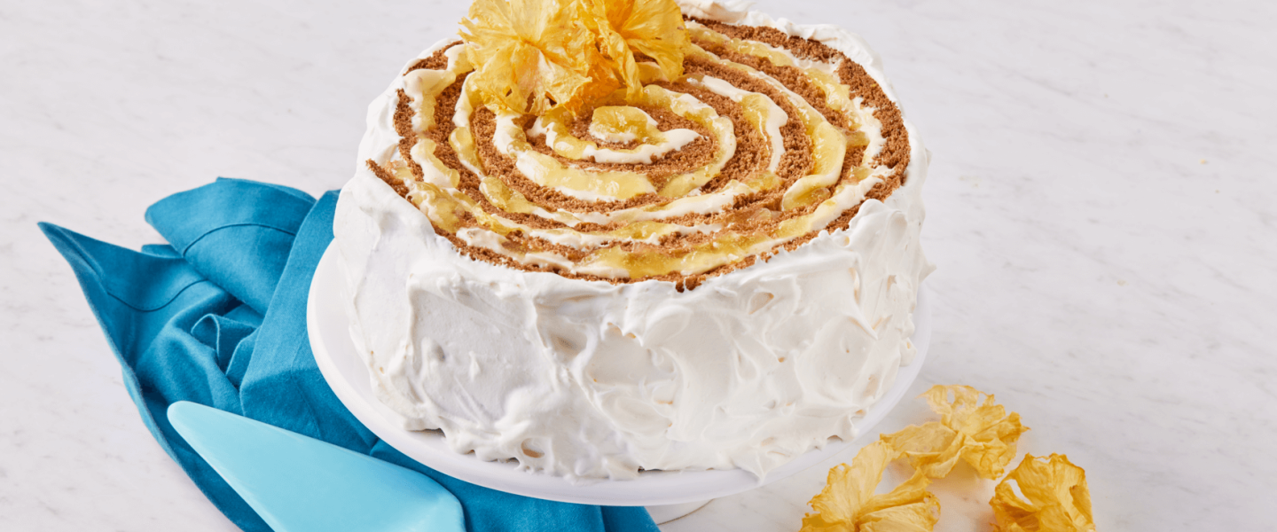 Un pastel en espiral con glaseado de tu proveedor de lácteos al por mayor, sobre un soporte con una servilleta azul.