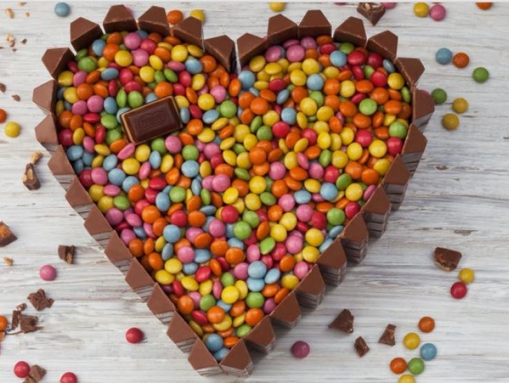 Keke en forma de corazón relleno de Manjar Nestlé® y decorado con chocolate Triángulo® y Lentejas® Mini