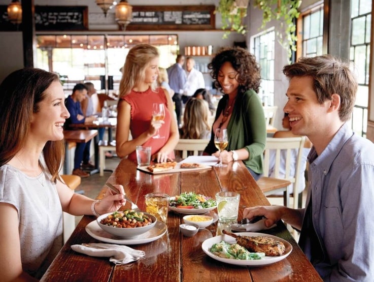 Personas sentadas en una mesa sonriendo y disfutando una comida juntos