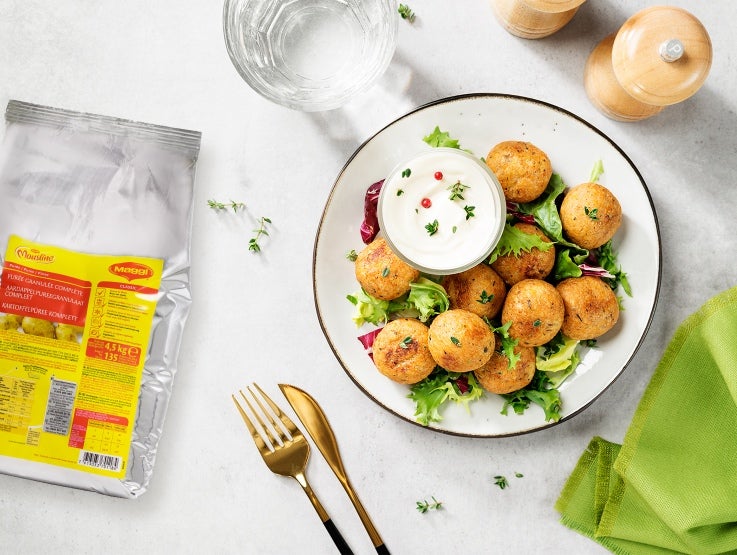 Plato de croquetas de papa junto a bolsa de Maggi Mousline Puré