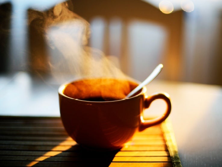 Taza de una bebida caliente y humeante con una cuchara en su interior